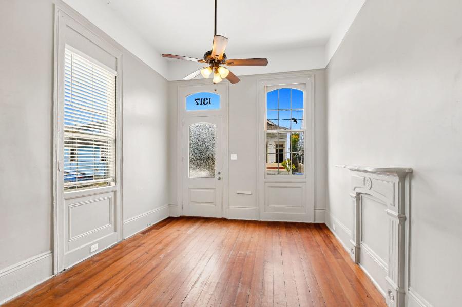 Front room with hardwood floors, ceiling fan and arched glass front doors