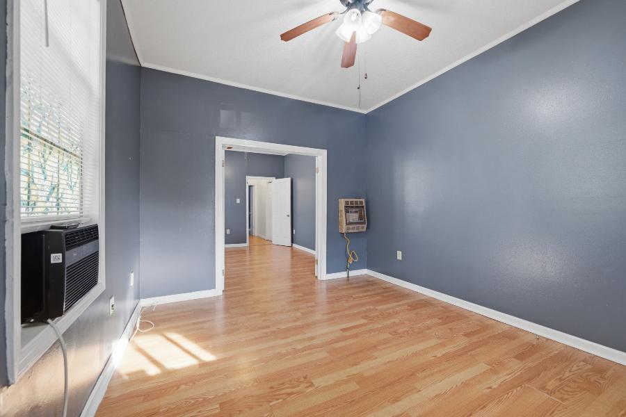 Room with ceiling fan and wall heater, looking through to the bedrooms