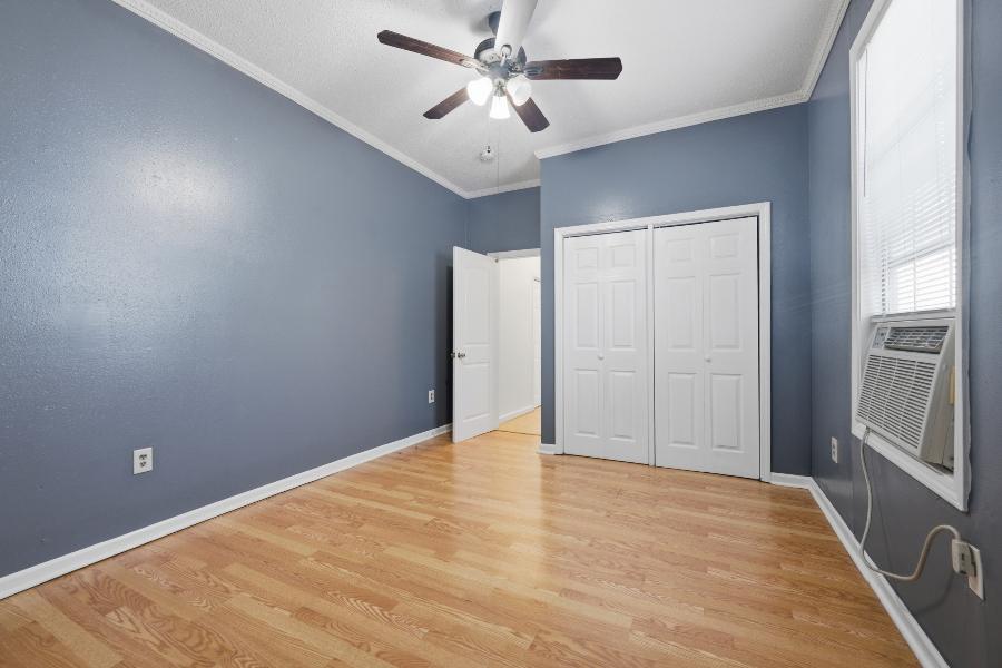 Bedroom with ceiling fan, double closet and window unit