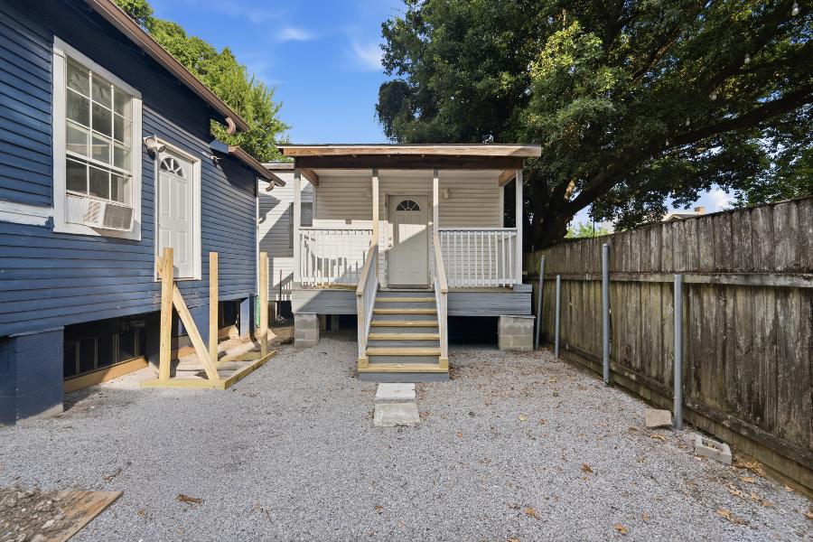 Gated, off-street gravel parking area leading to the apartment porch