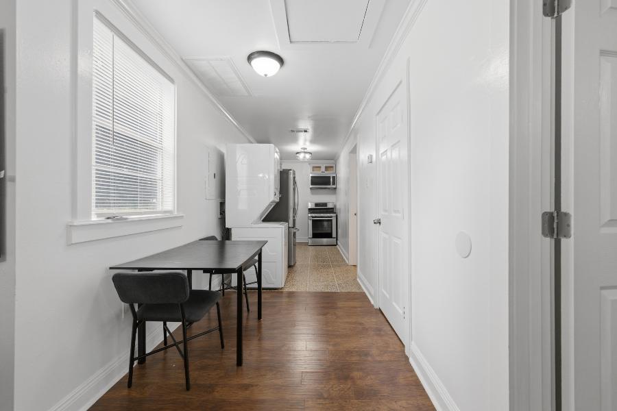 Dining area with table and chairs, stacked washer and dryer, and the kitchen beyond