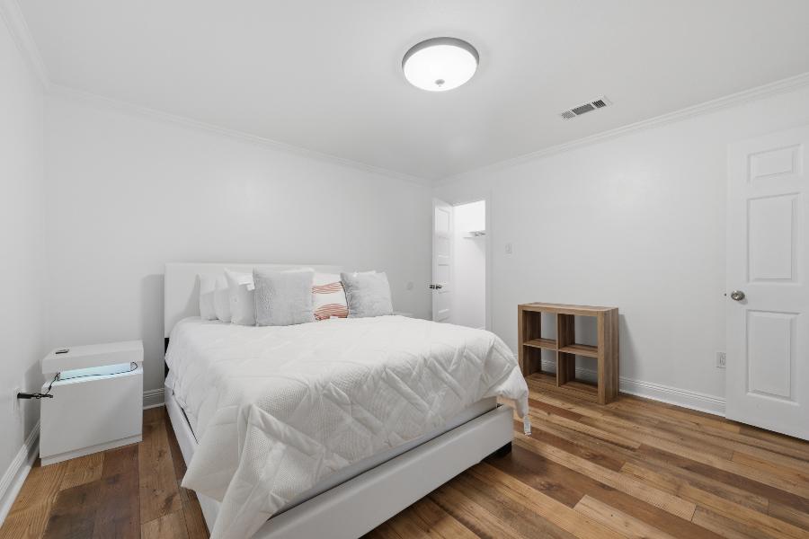 Second bedroom with white bed and nightstand