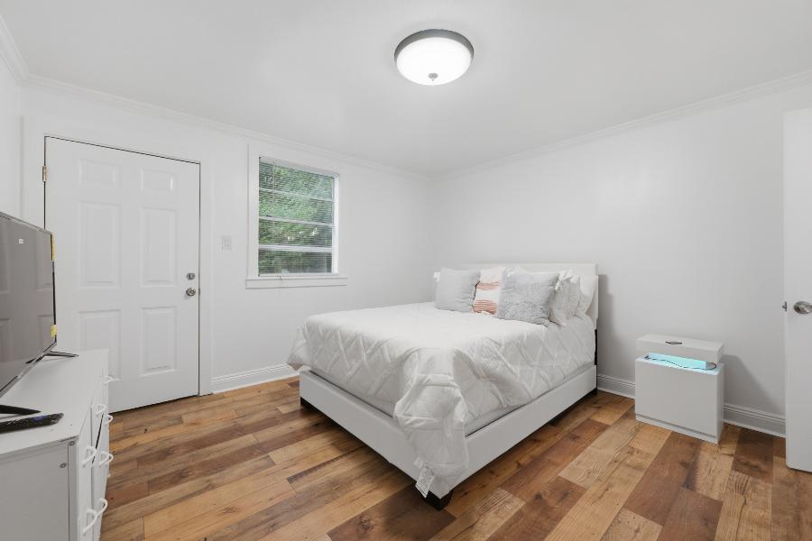 Bedroom with white bed, dresser and TV