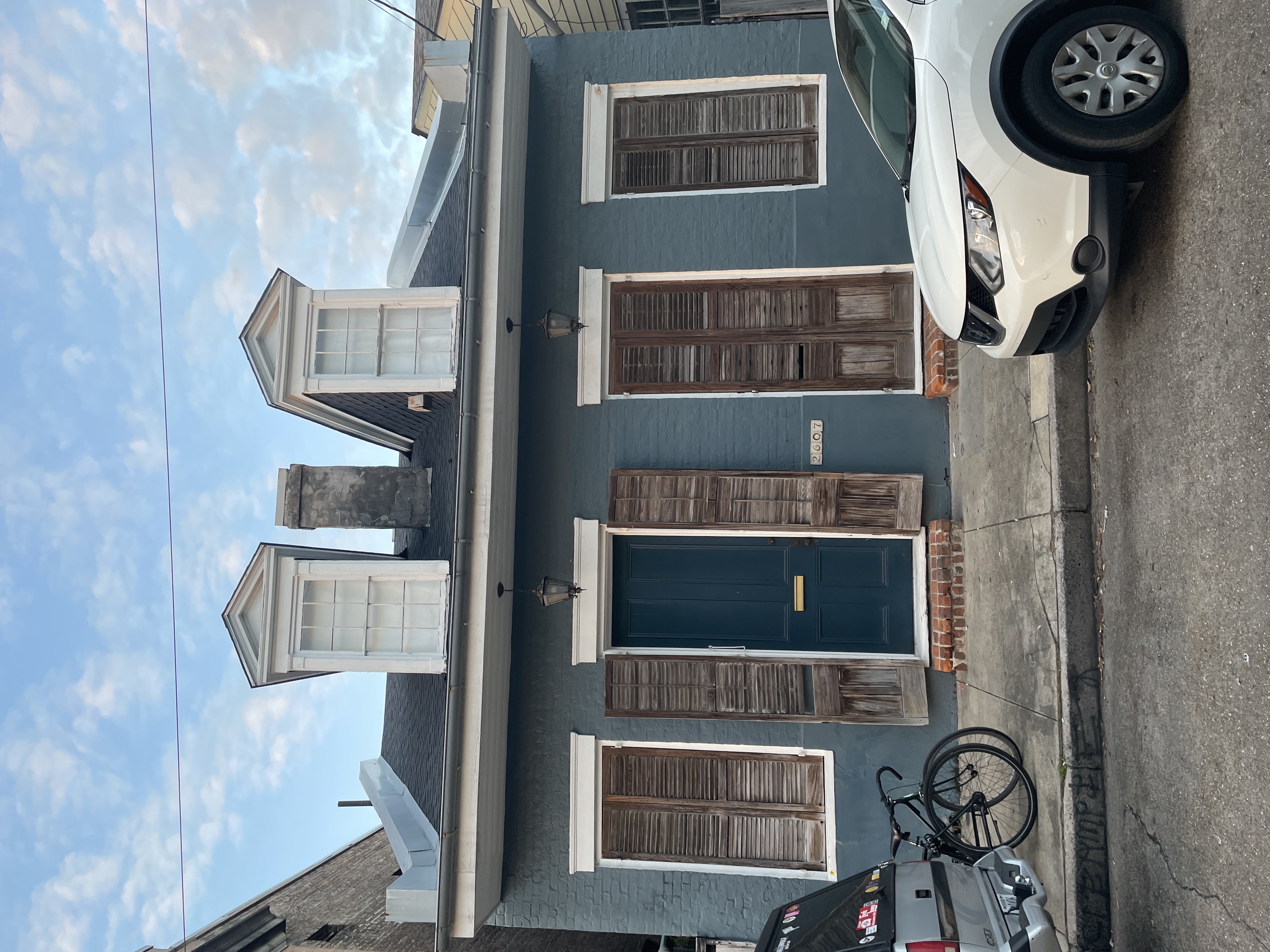 Historic Creole cottage with dormer windows, weathered shutters, and a deep blue facade in the Bywater, New Orleans