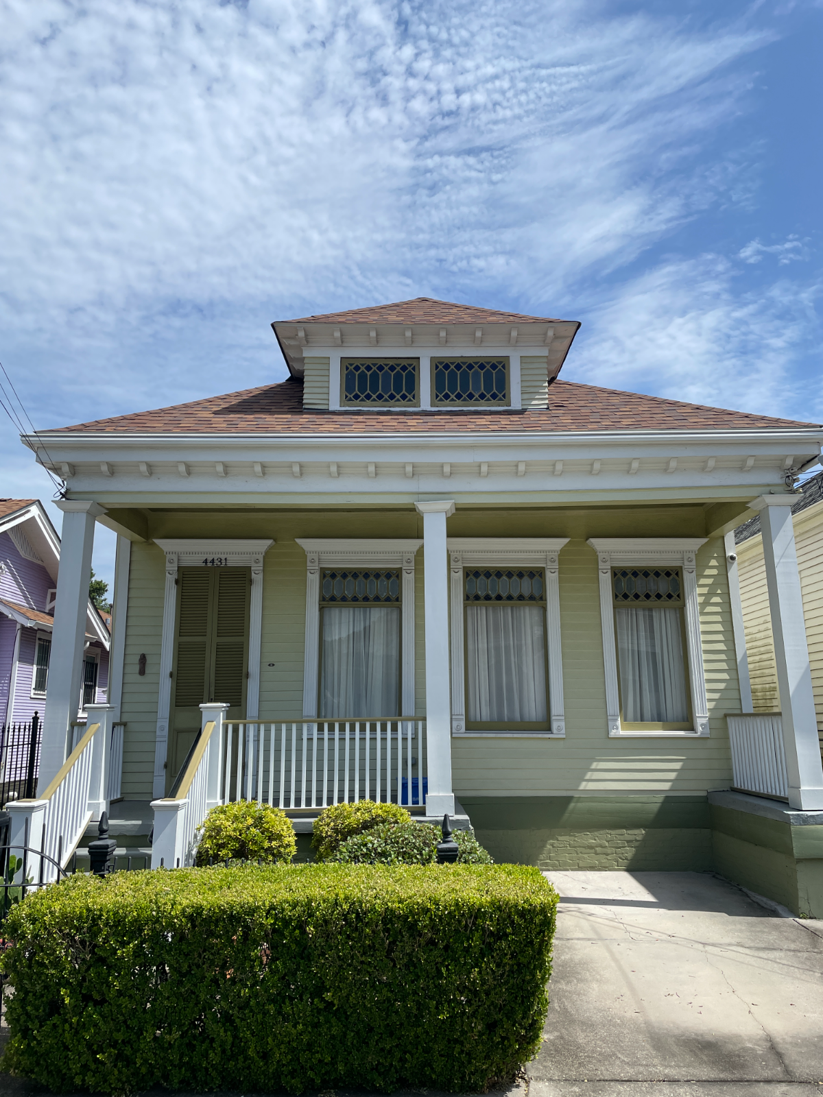 A restored green Craftsman cottage with a front porch on Freret Street in New Orleans